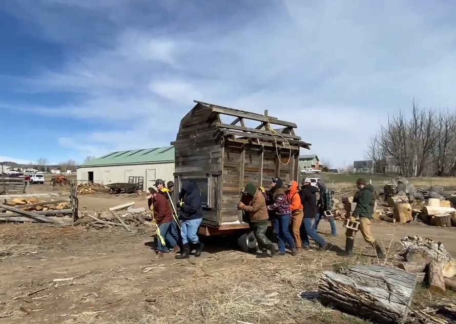 A group of people carry a chicken coop